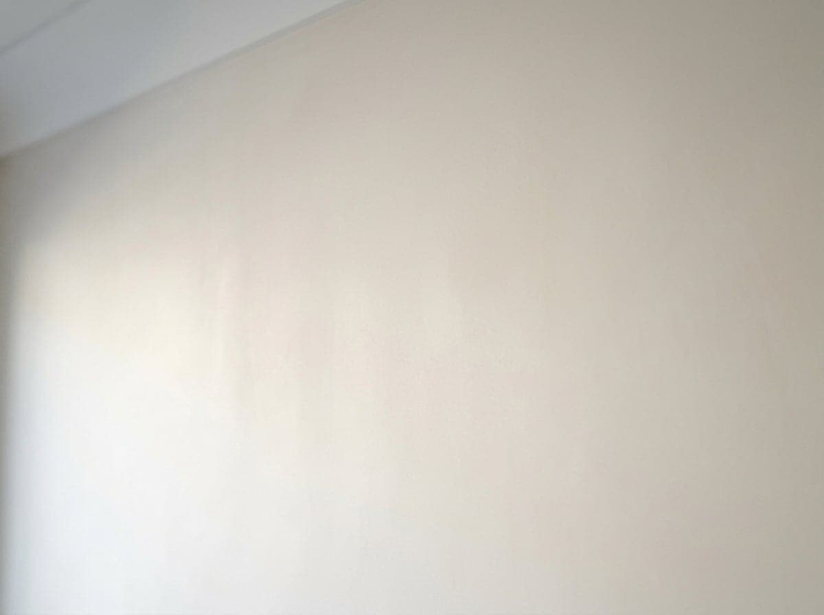 Detail einer Innenputzwand in Q3-Qualität im Streiflicht, sichtbar gleichmäßig glatte Oberfläche ohne sichtbare Strukturen.